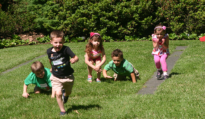 Children running in a race on a green lawn during summer camp