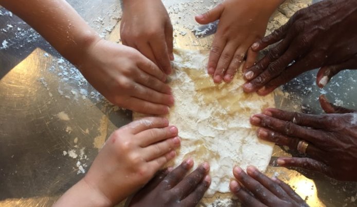 Kids pressing and flattening a pie crust together